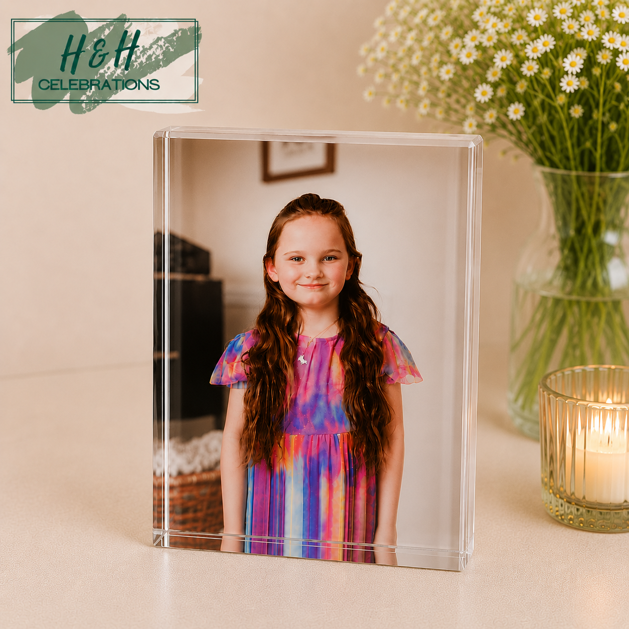 Acrylic photo block with a young girl in a colorful dress, placed on a surface with a vase of flowers and candle in the background.